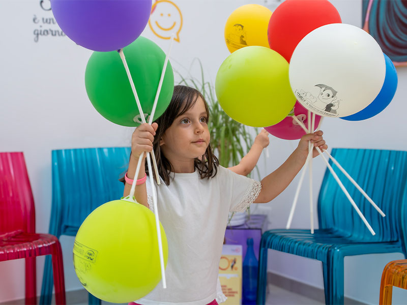 Bambina sorride con palloncini colorati